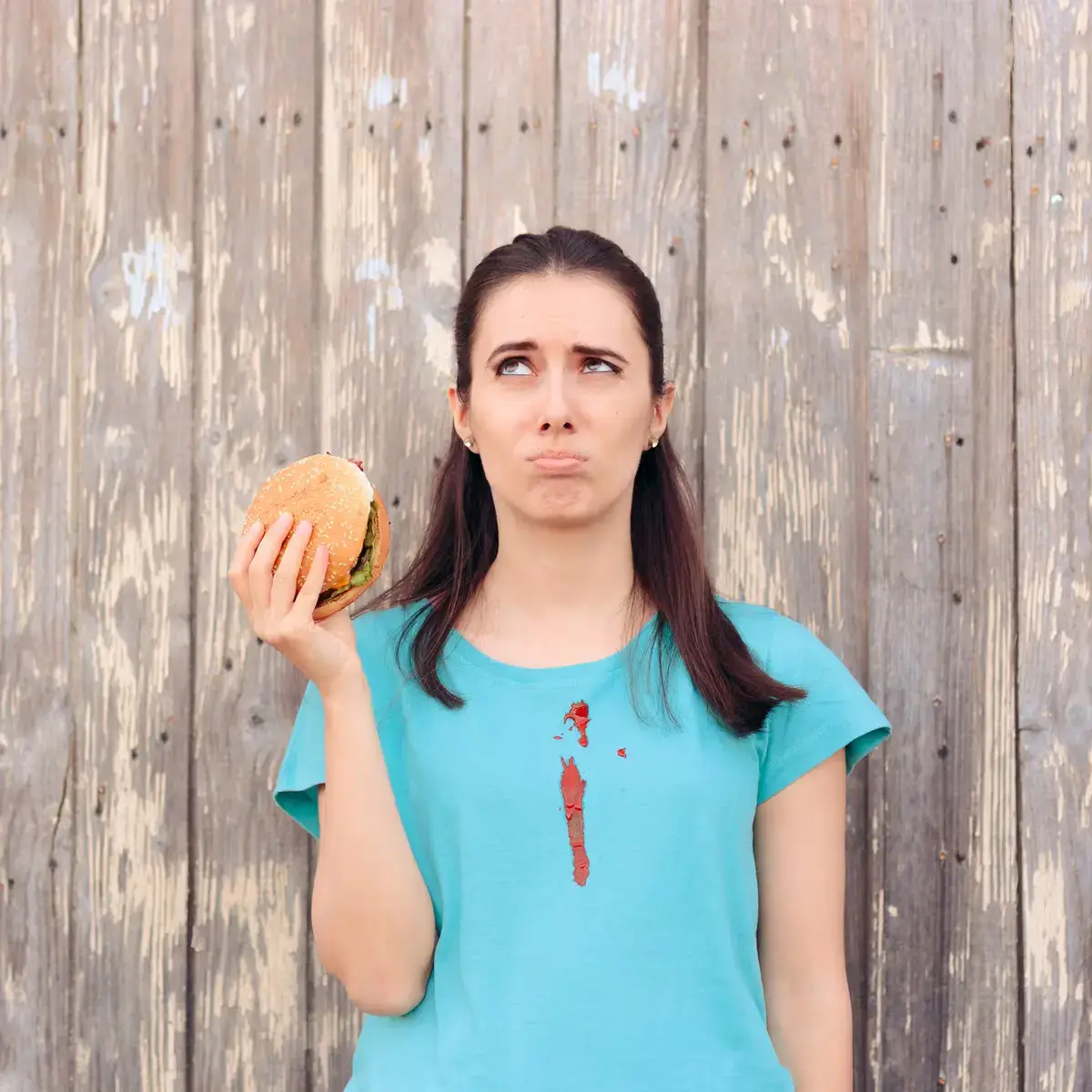 tomatensauce aus kleidung entfernen hausmittel frau isst burger hat ketchup fleck auf t shirt