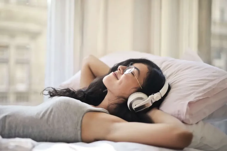entspannungsmusik zum einschlafen frau liegt im bett hoert musik gluecklich