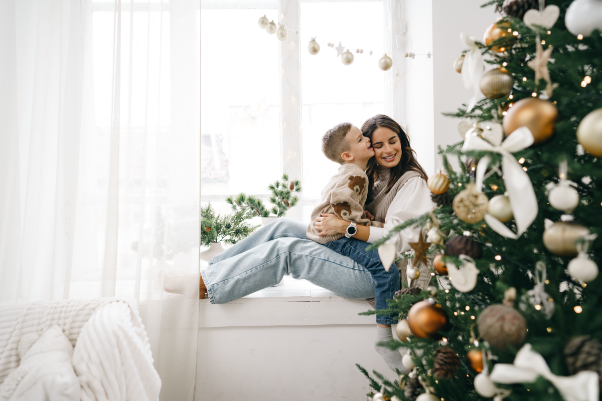 happy mother with son sit windowsill near christmas tree