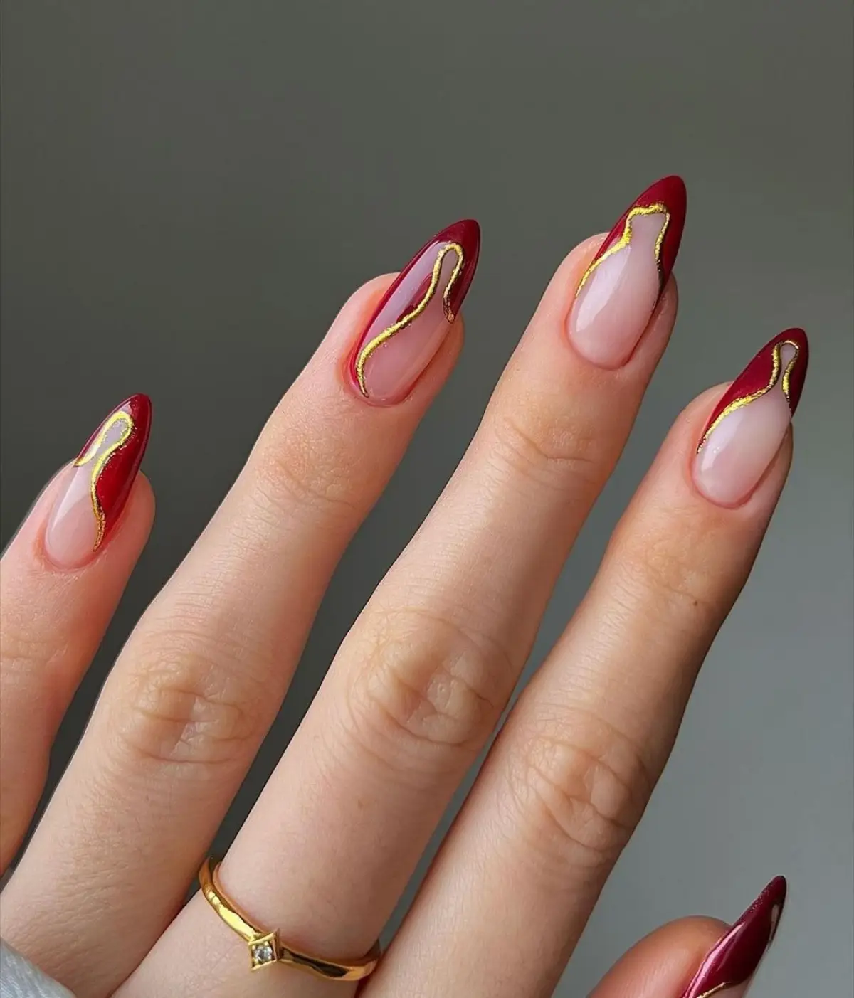 nageldesign weihnachten und silvester 2023 french manicure in dunkelrot mit golden linien asymmetrisch