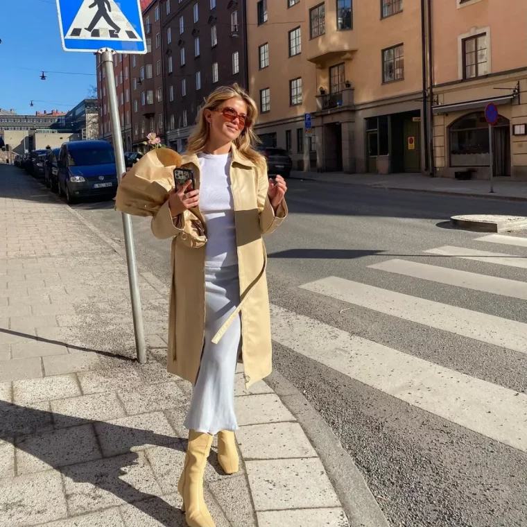 welche wintermaentel sind 2023 angesagt junge frau wintermantel aus leder beige mit stiefeletten in derselben farbe weisse bluse und rock