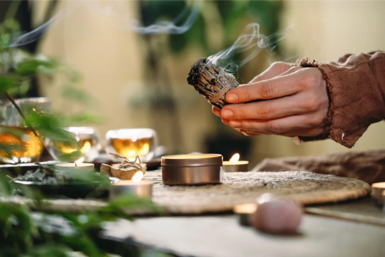 frau mit salvia, kerzen und tee, um die negative energie in ihrem haus zu beseitigen