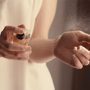 frau sprüht parfüm auf handgelenke