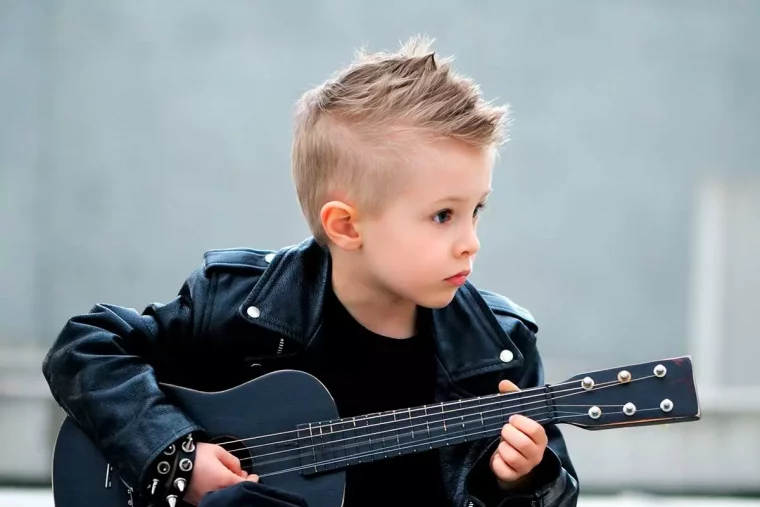kleiner junge mit cooler frisur, lederjacke und schwarzer gitarre