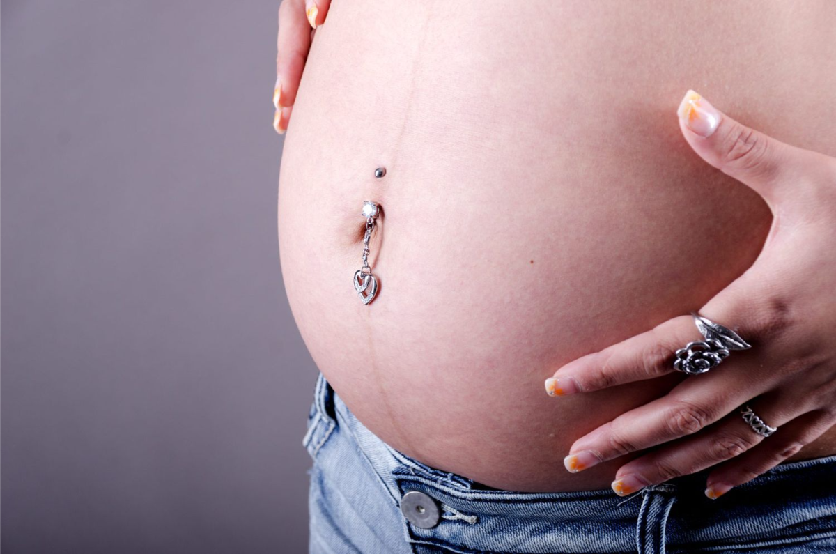 schwangere frau mit bauchnabelpiercing