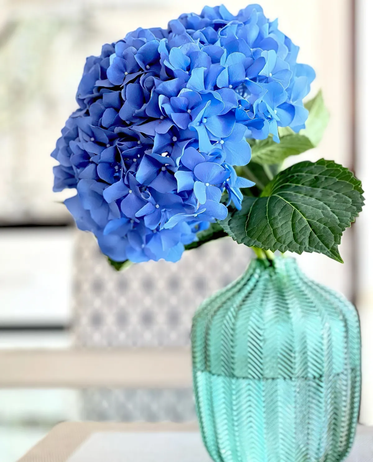 Decorate the dining table with blue hydrangeas in a glass vase.