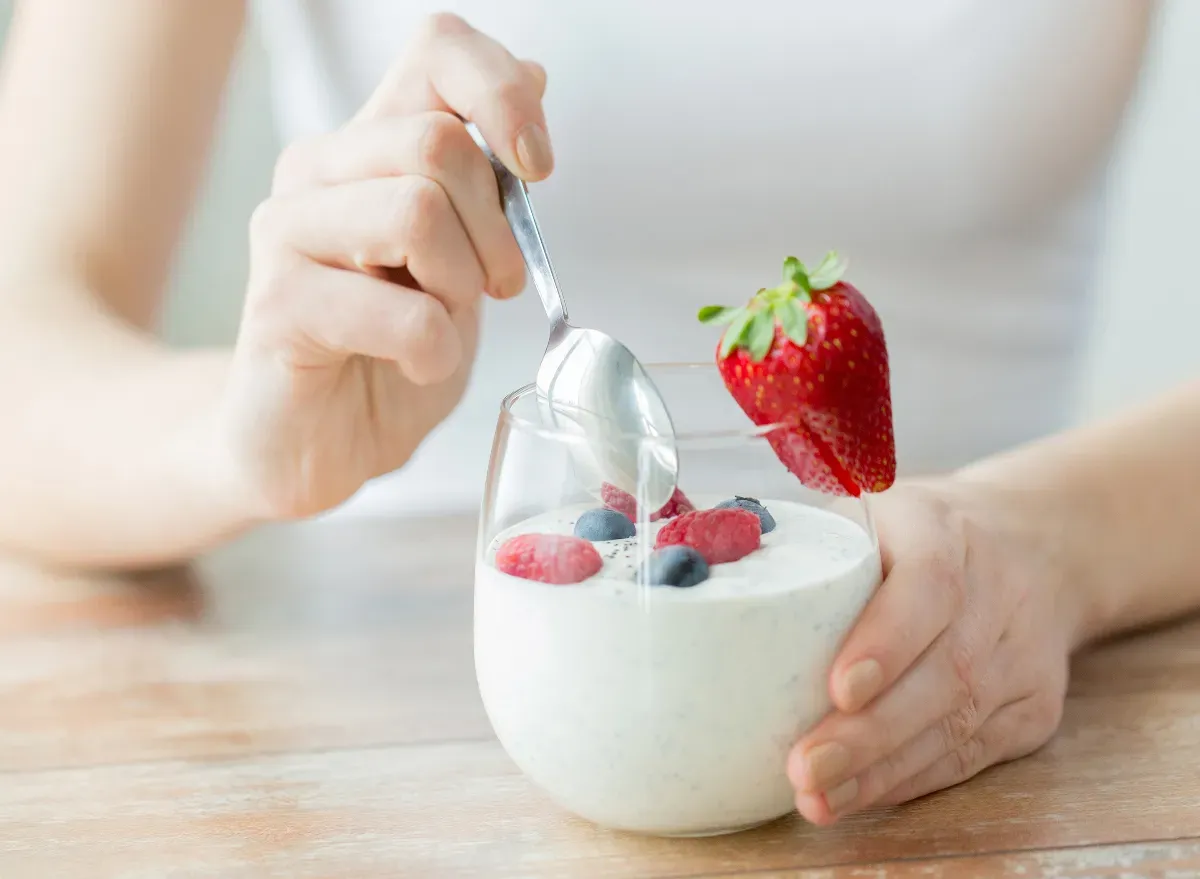 frau isst joghurt mit blaubeeren und erdbeeren