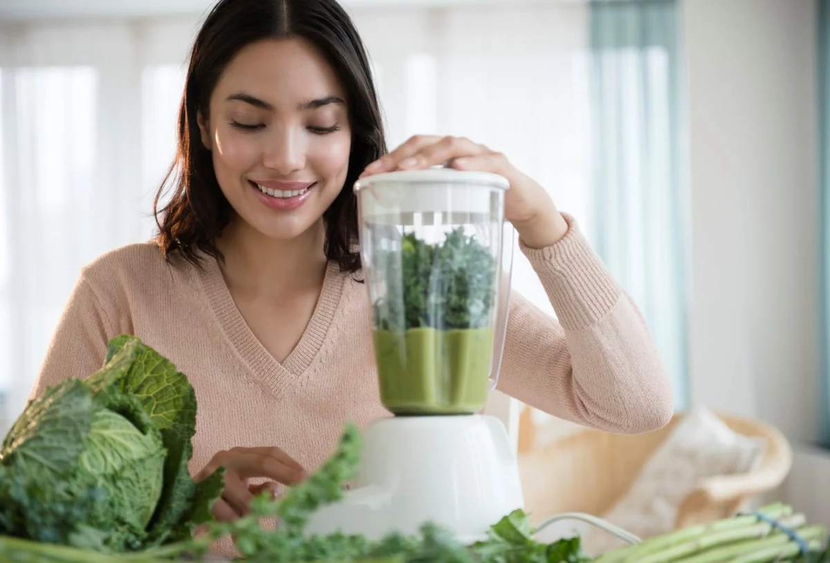 junge frau macht sich gruenkohl smoothie