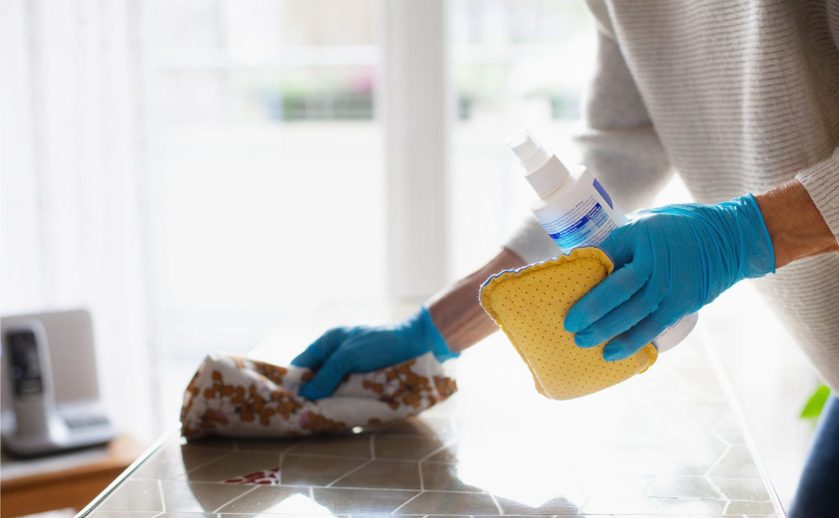 frau mit blauen gummihandschuhen beim reinigen der küche