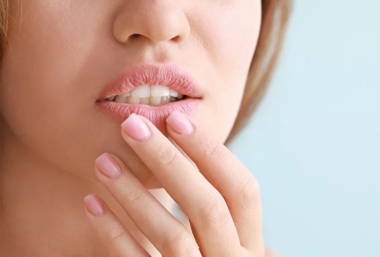 frau mit rosa nagellack, die ihre rissigen lippen berührt