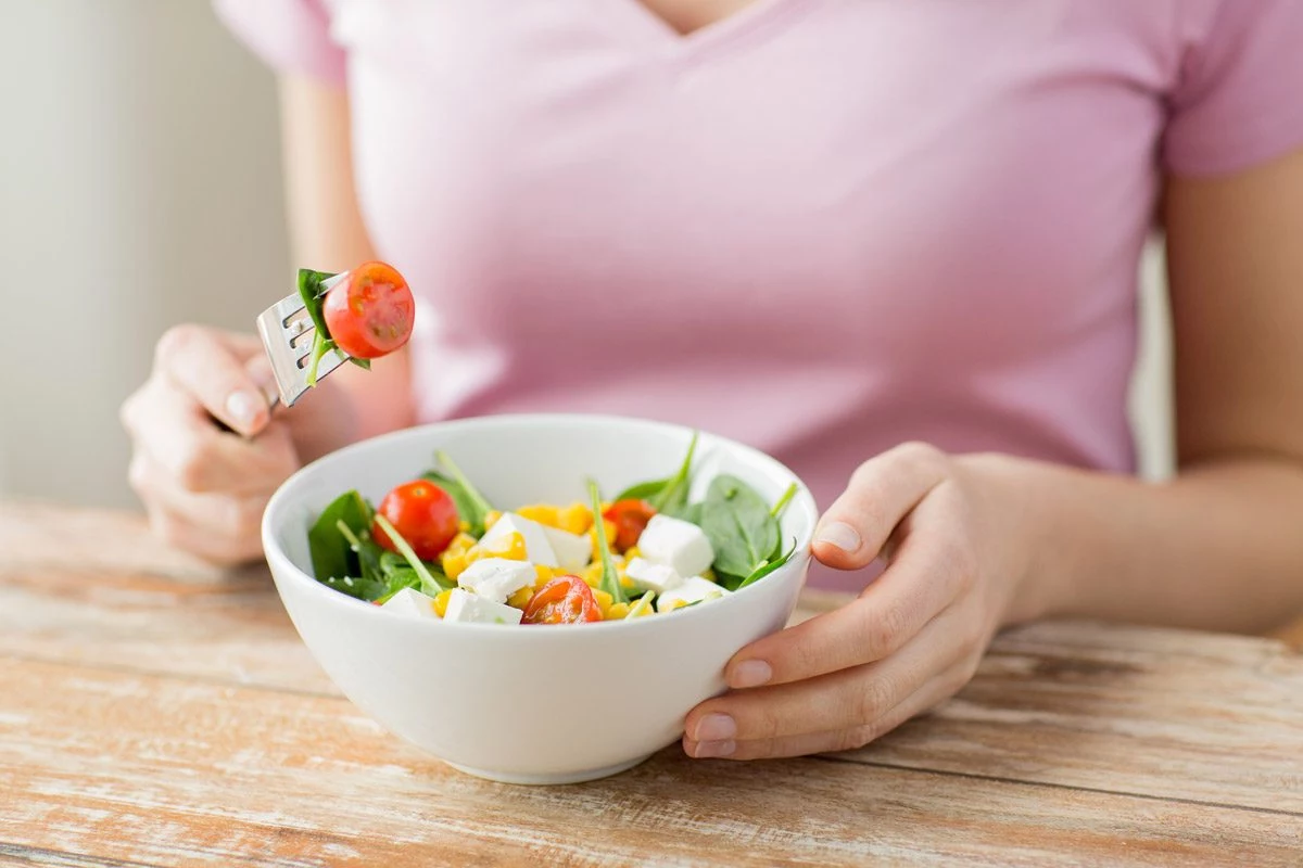 frau isst kleinen salat mit feta und gemuese