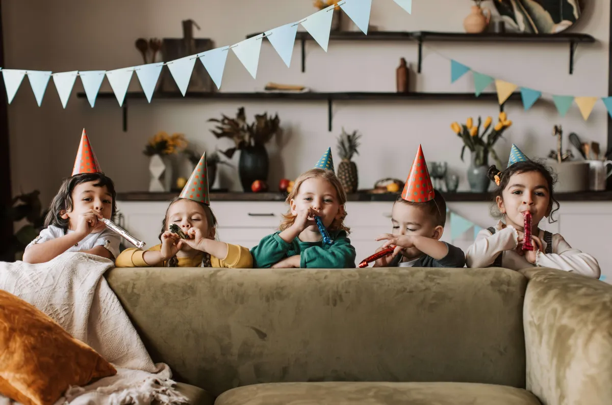 kinder feiern zusammen partyhüte papiergirlande deko