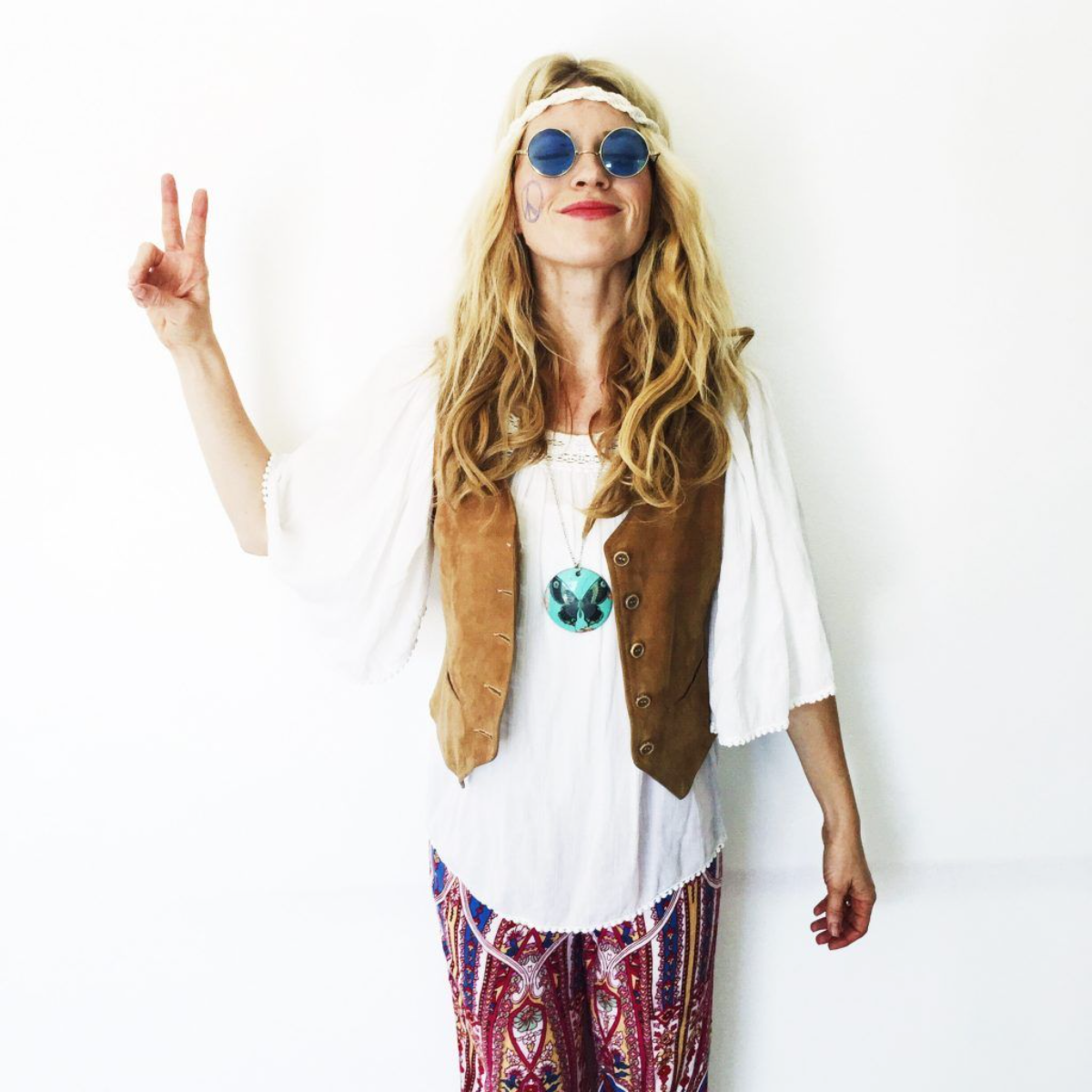 frau mit hippie kostüm zeigt friedenszeichen
