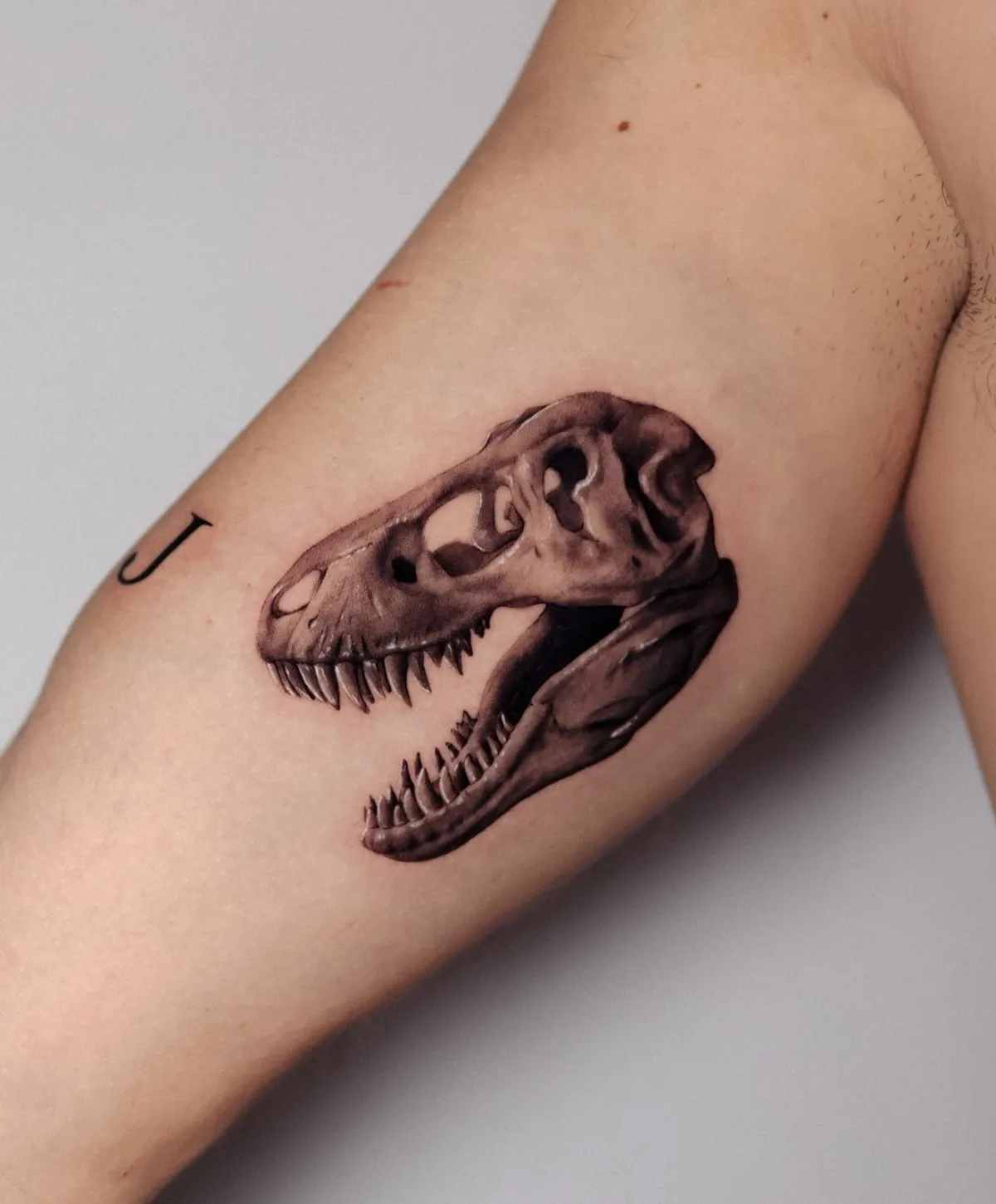 dino tattoo am oberarm motiv für männer