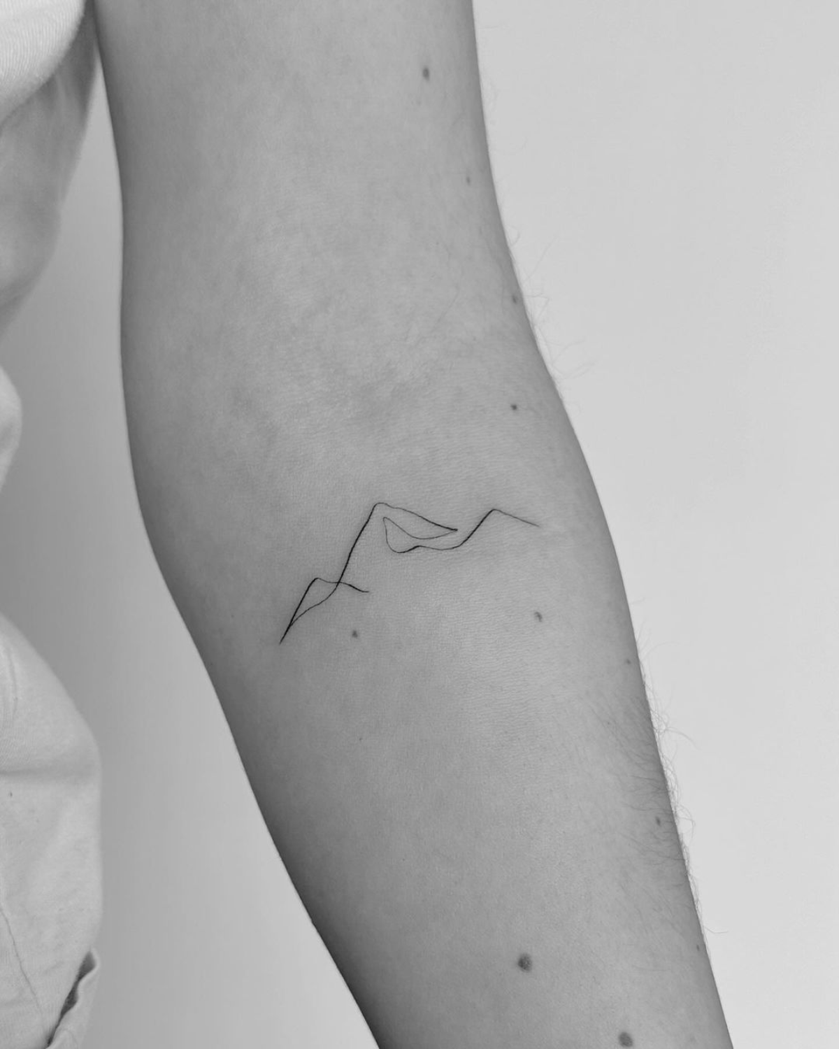 minimalistisches one line tattoo mit bergen