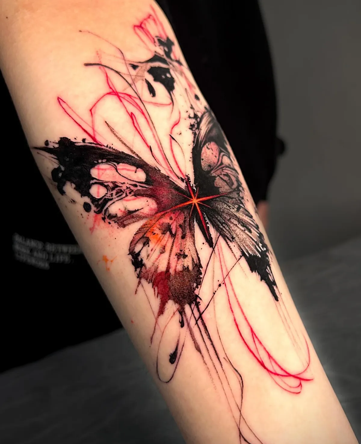 aquarell tattoo am unterarm schmetterling schwarz und rot