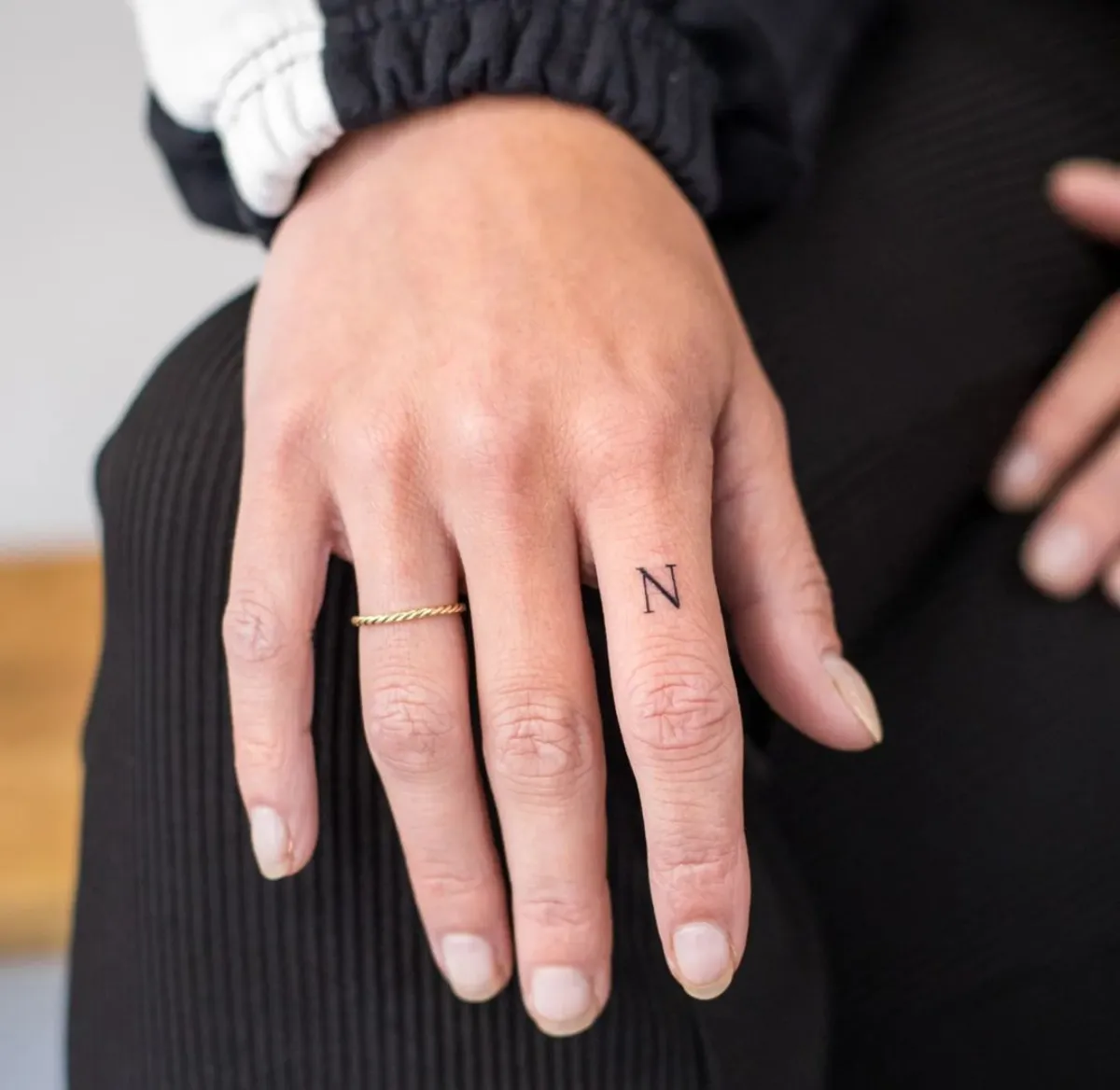 buchstaben tattoo am zeigefinger minimalistisch