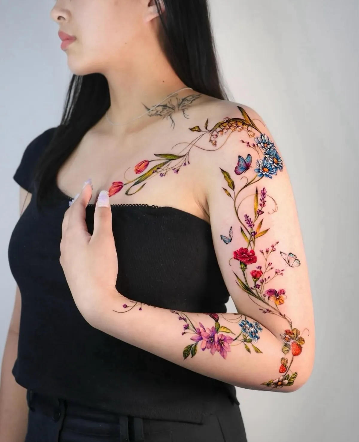 full sleeve tattoo bunte frühlingsblumen schmetterlinge erdbeeren