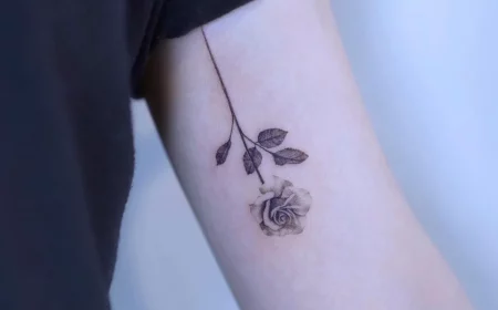 kleines rosen tattoo am oberarm frauen motiv