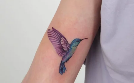 kolibri tattoo in blau und lila am oberarm frau