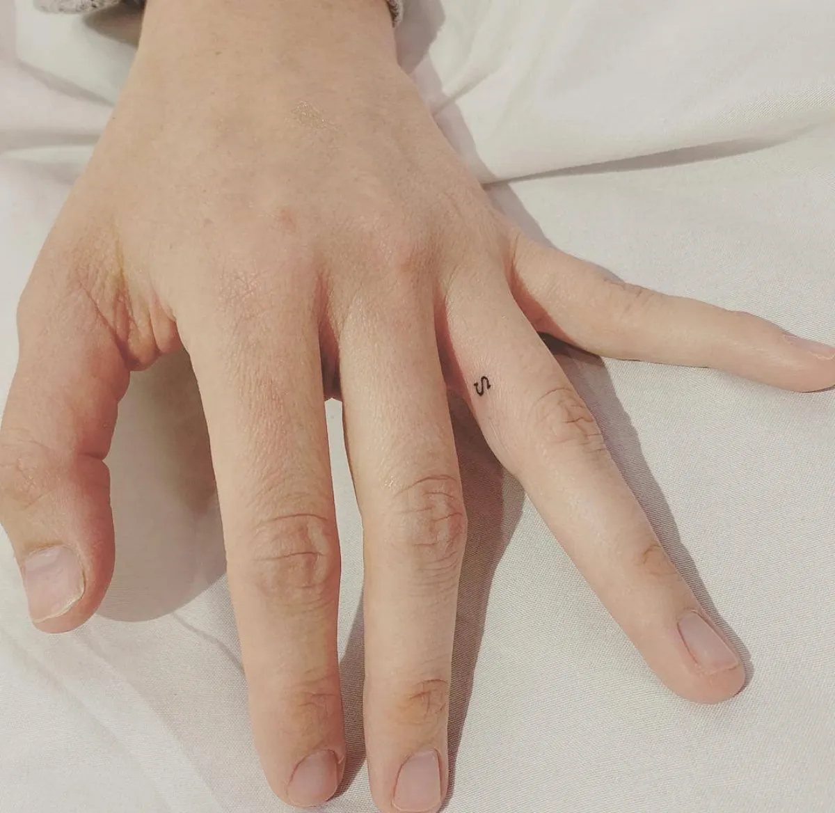 minimalistisches tattoo am finger buchstabe