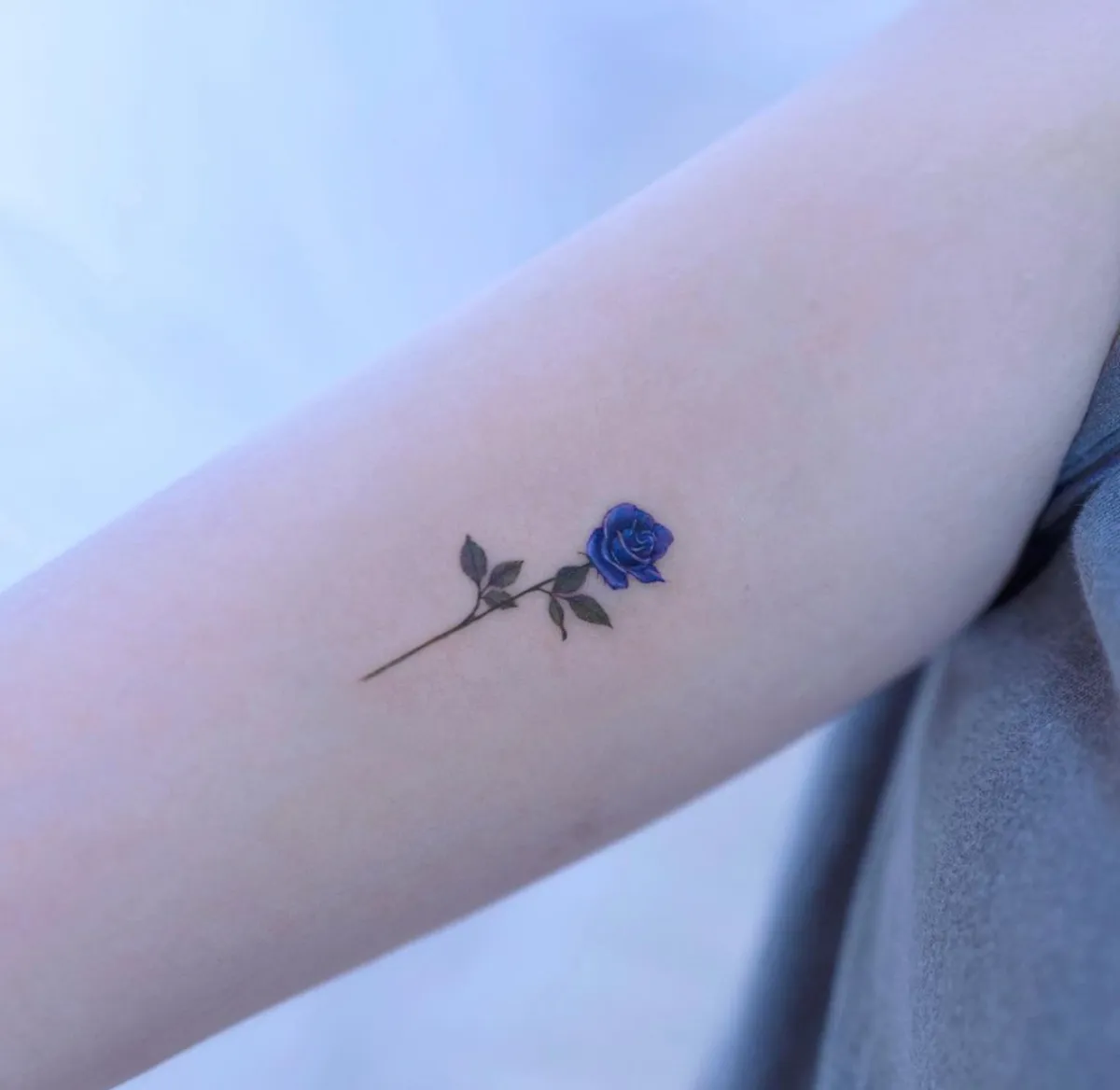 minimalistisches tattoo am oberarm blaue rose