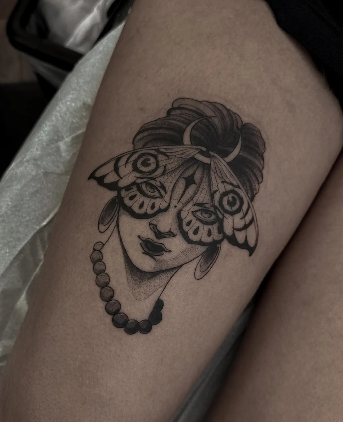 oberschenkel tattoo frau mit schmetterling maske und perlenkette