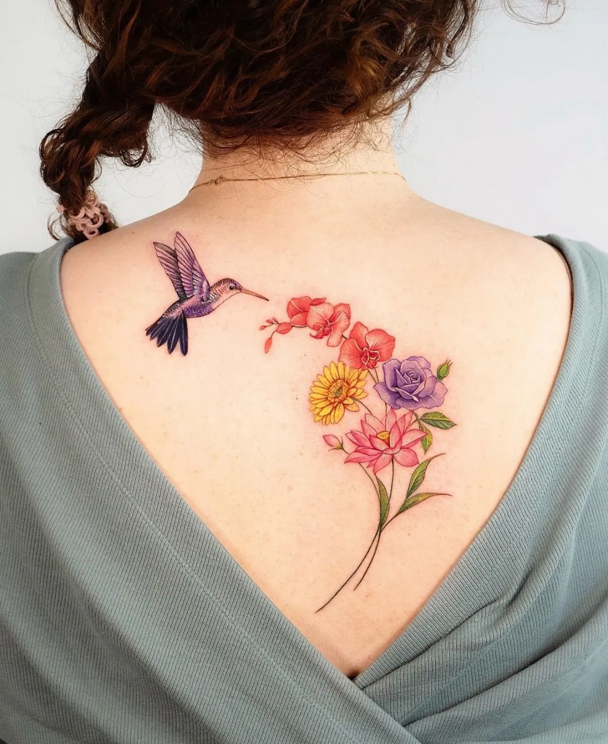 rücken tattoo frau kolibri mit blumenstrauß bunte blumen