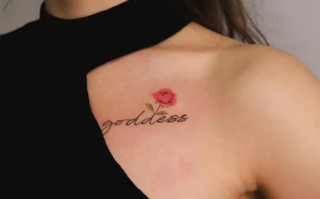 schriftzug tattoo mit kleiner rotoer rose am brust goddess
