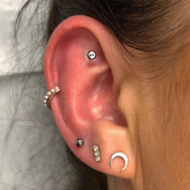 verschiedene piercings am ohr einer frau