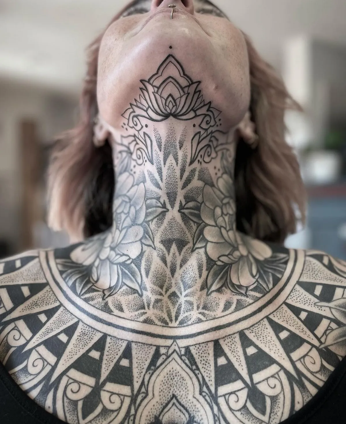 blackwork tattoo massiv blumen motiv am hals und dekollete