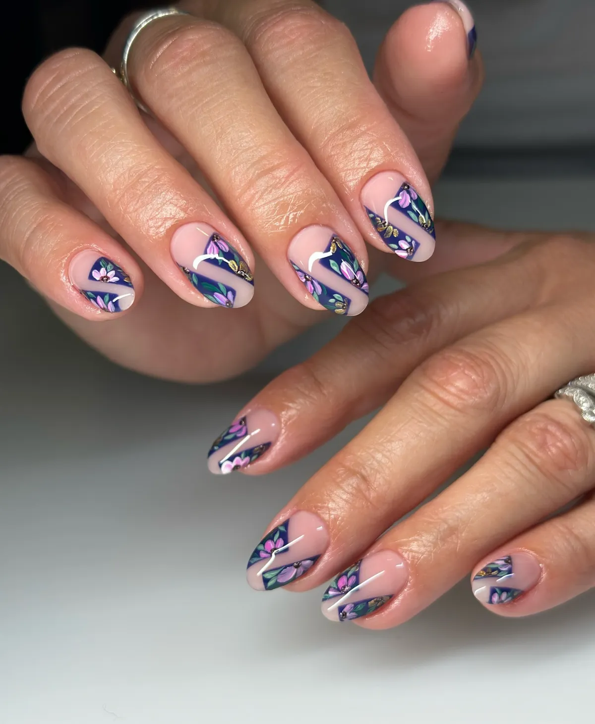 nageldesign mit blumenmuster dunkelblauer akzent auf nude nägeln