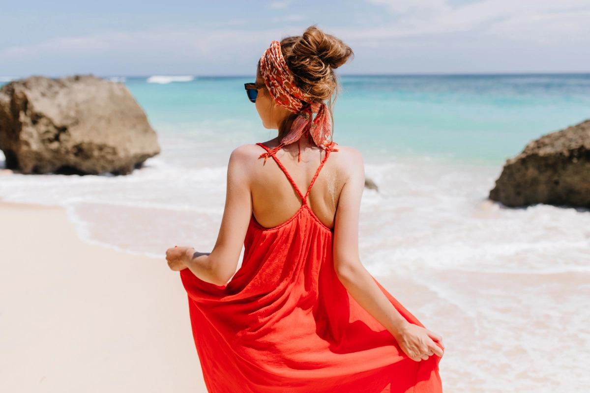 sonnenschutz und mode frau am strand mit rosem kleid