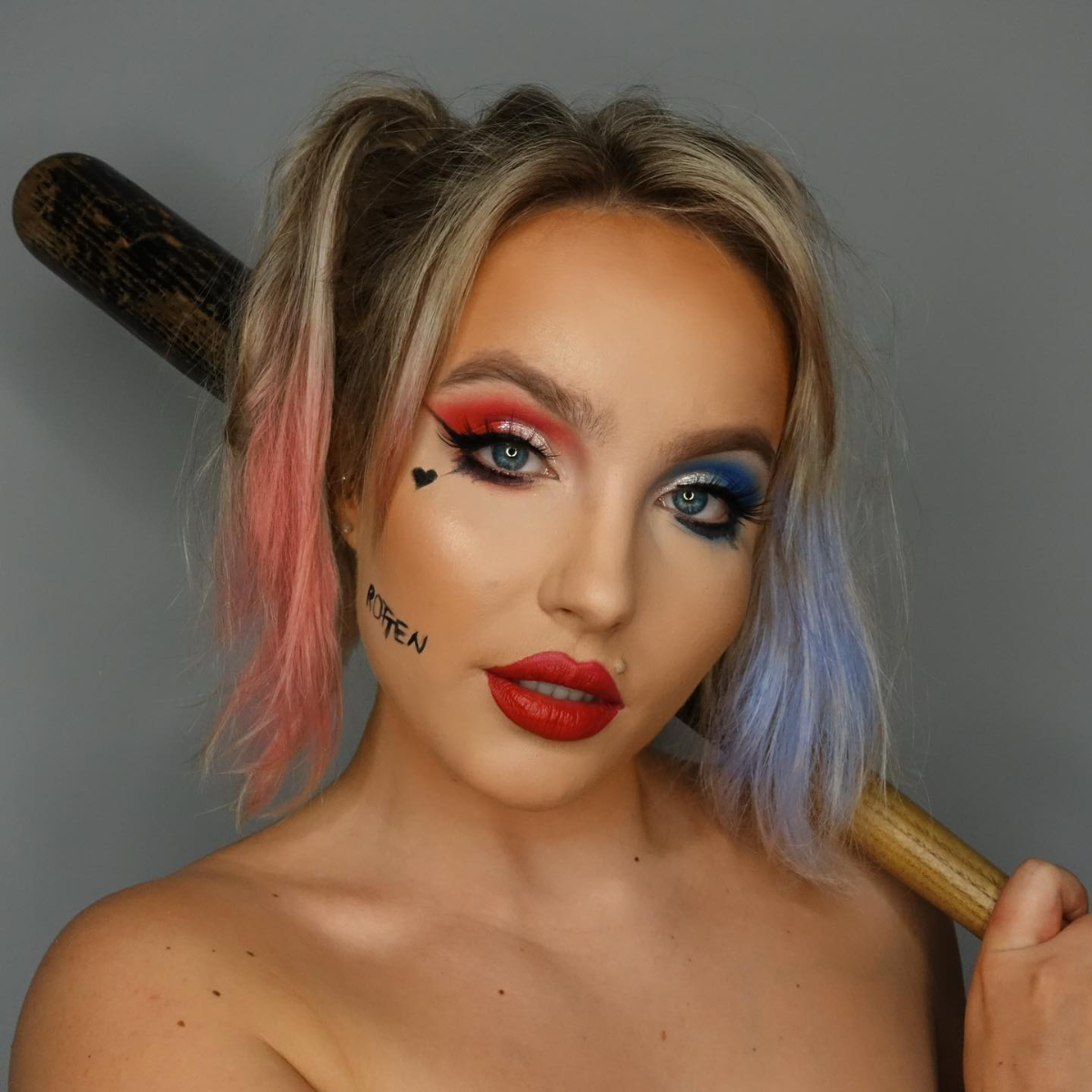 frau mit harley quinn make up hält einen schläger