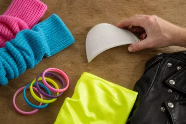 Hände arrangieren Schulterpolster, Stulpen und bunte Plastikarmreifen