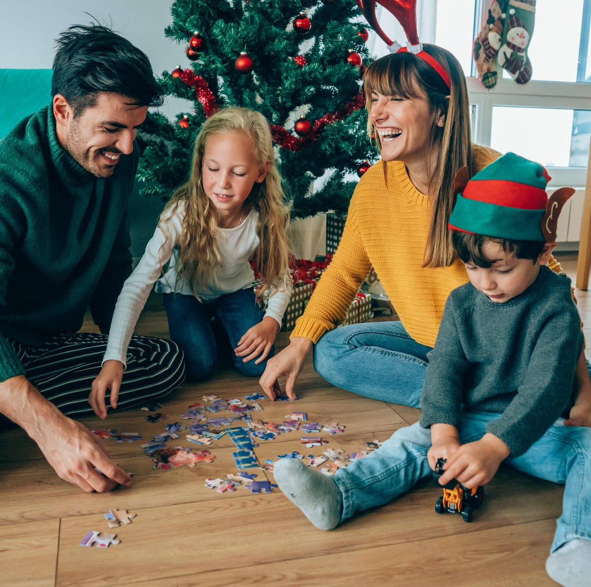 familie macht puzzle an weihnachten vor dem weihnachtsbaum