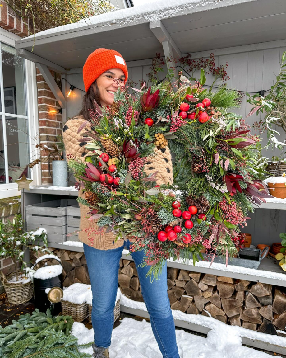 frau hält großen schön geschmückten adventskranz