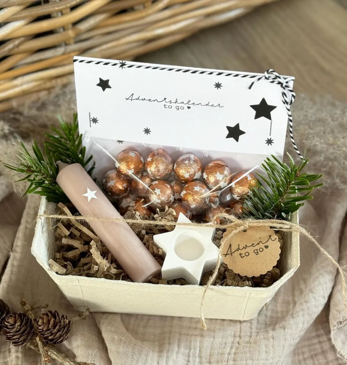 geschenkkorb für weihnachten mit schokoladenpralinen duftkerzen und tannenzweigen