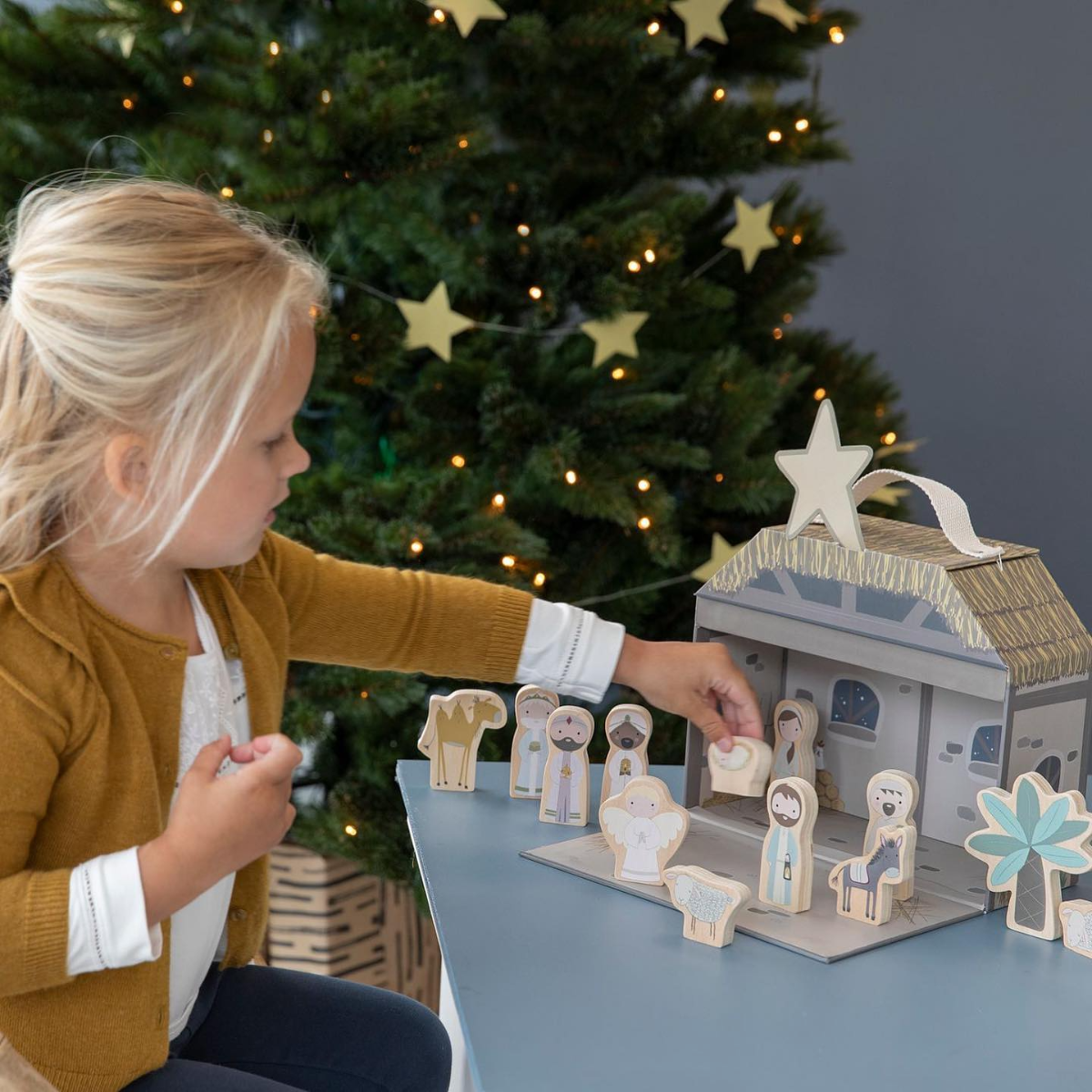 kleines mädchen spielt mit weihnachtskrippe aus holz