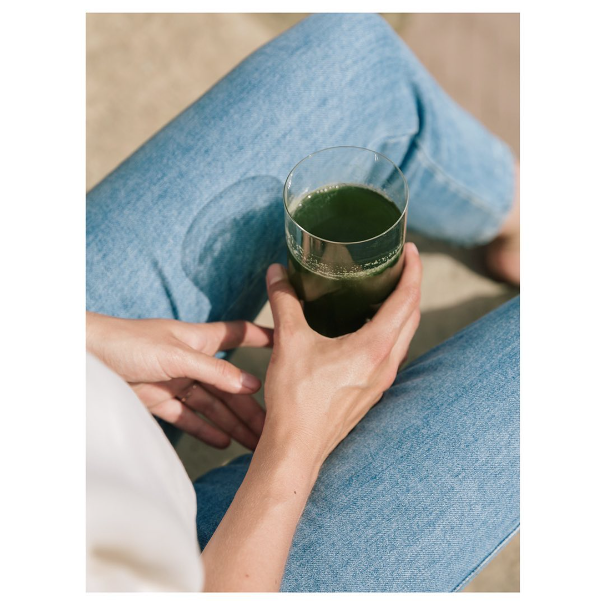 frau hält ein glas mit grünem saft