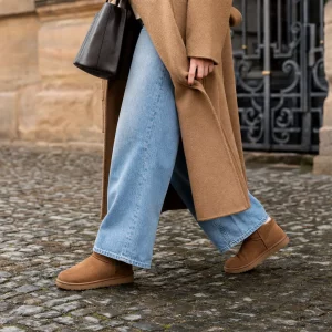 Frau kombiniert Ugg Boots mit Wide-Leg-Jeans im winterlichen Streetstyle-Look