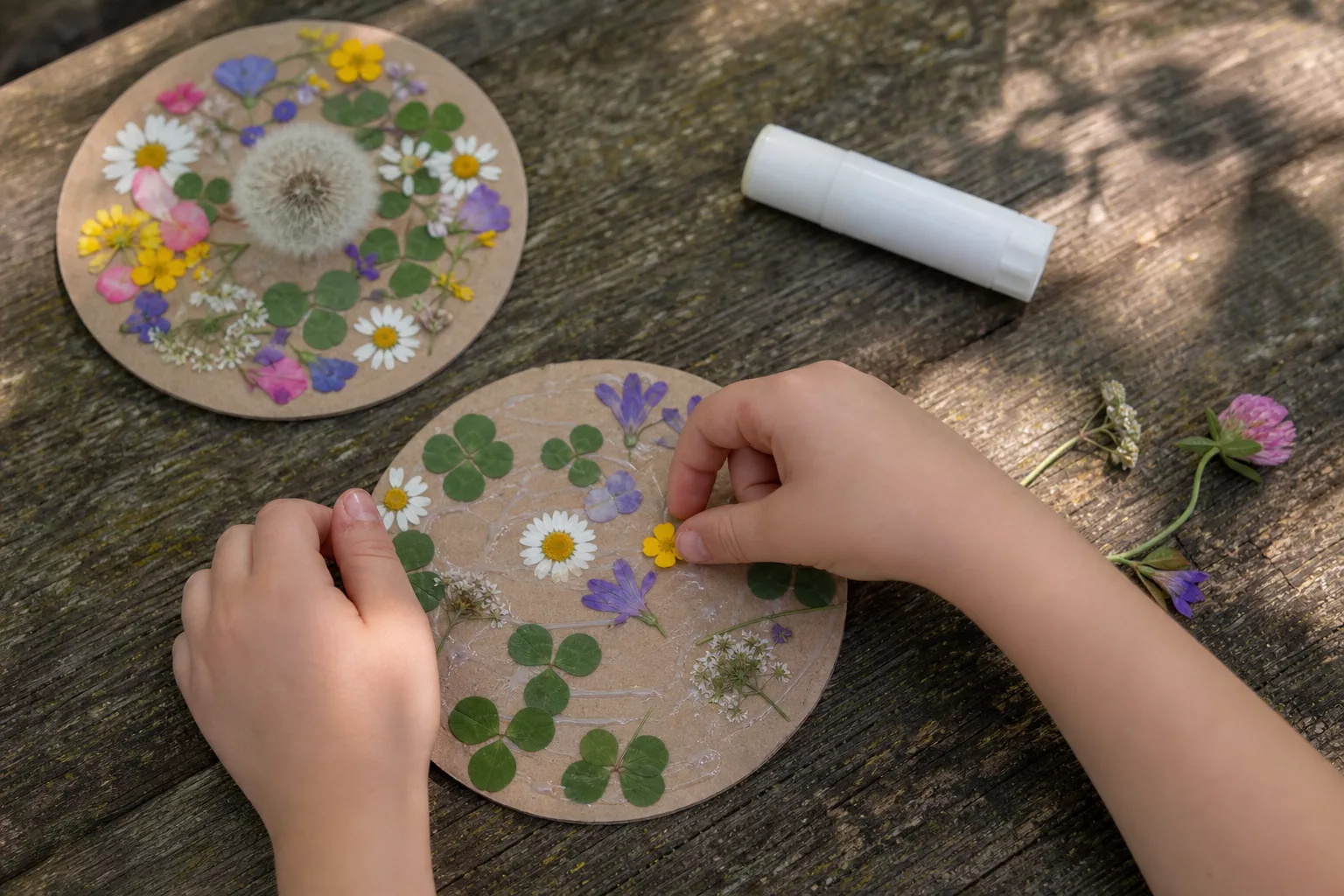 Kinderhände legen frische Sommerblumen auf einen Pappkreis