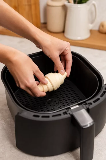 Hände legen ein TK-Croissant direkt in den Airfryer