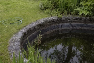 Gartenteich mit abgesenktem Wasserstand im Frühsommer
