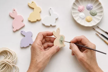 Hände bemalen Holz-Hasenformen für eine Osterhasen-Girlande