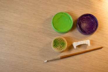 Grüne und violette Monster-Schminkfarbe mit Fake-Zähnen und Schwamm