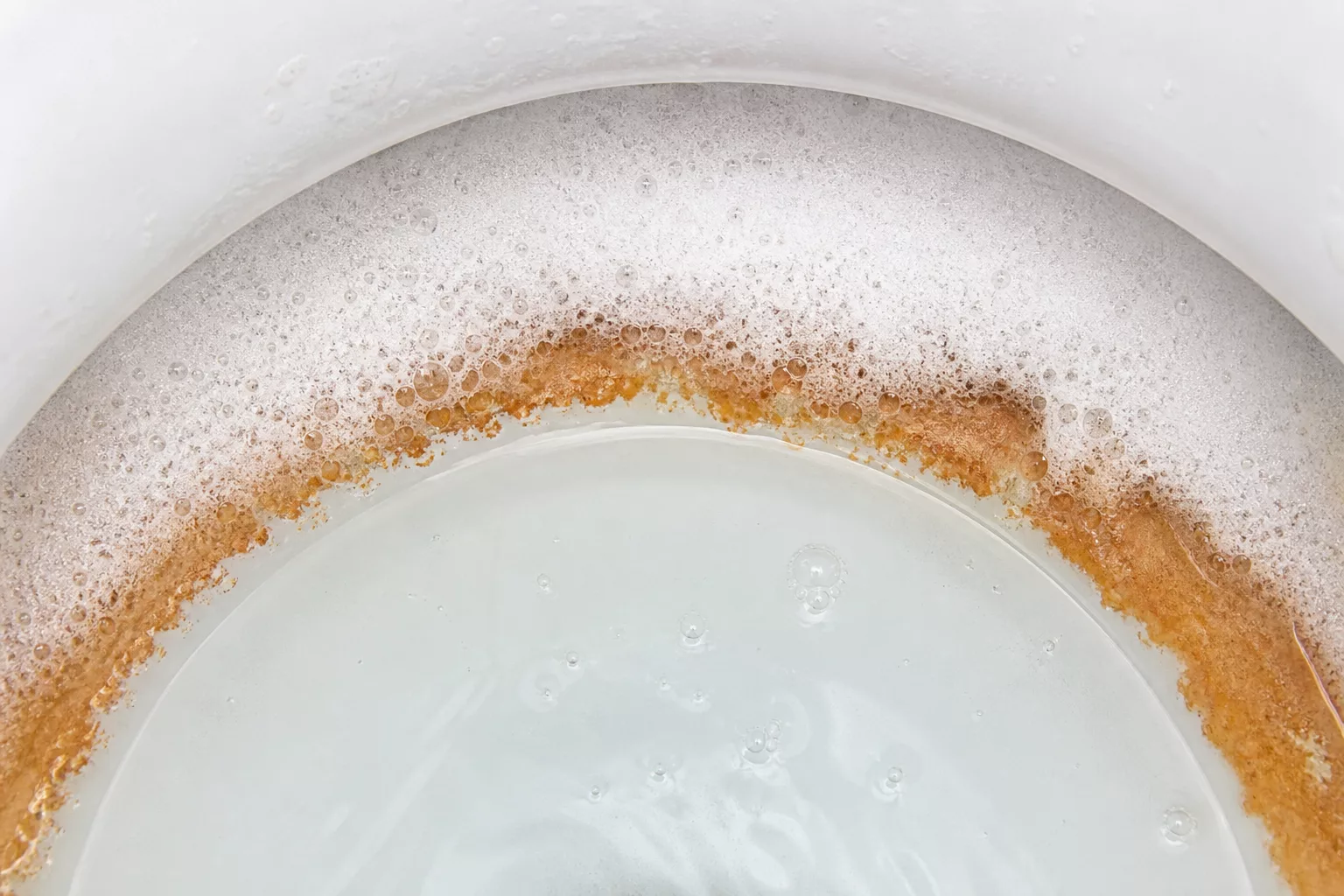 Nahaufnahme eines Kalkrings, der sich im Reinigungsschaum auflöst