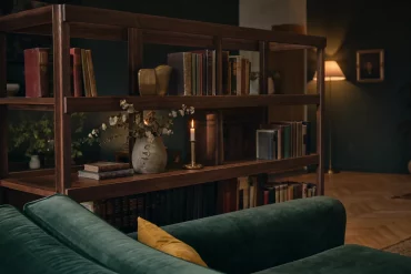 Dunkles Bücherregal hinter Samtsofa im Bibliotheksstil