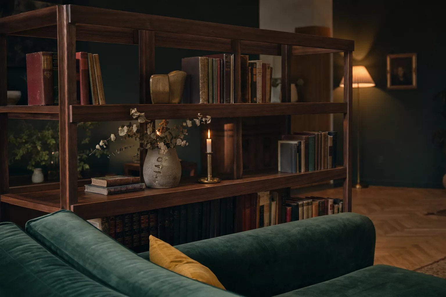 Dunkles Bücherregal hinter Samtsofa im Bibliotheksstil