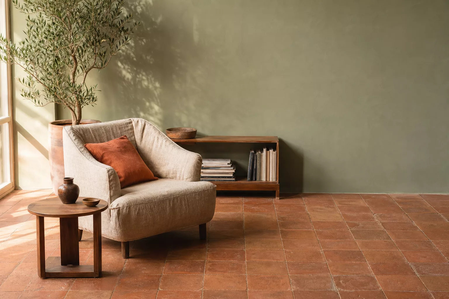 Wandfarbe Salbeigrün kombiniert mit warmen Terracotta Fliesen im Wohnzimmer